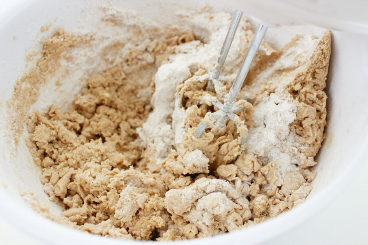 Cookie dough being combined in a large bowl with a hand mixer.