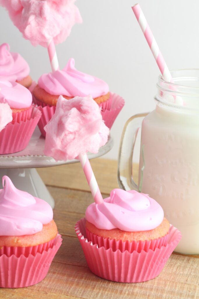 Cotton candy cupcakes featuring a strawberry cake filled with cotton candy and topped with vanilla icing for a fun treat.