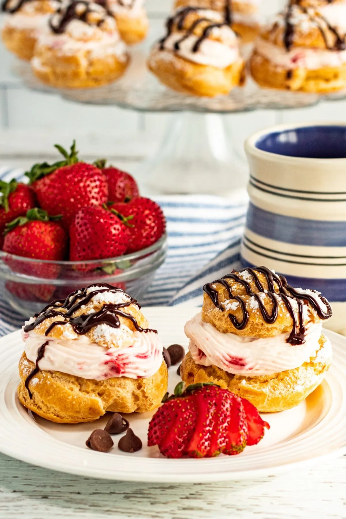 These Strawberry Cream Puffs feature a light, flaky pastry filled with strawberry whipped cream, topped with a chocolate ganache drizzle.