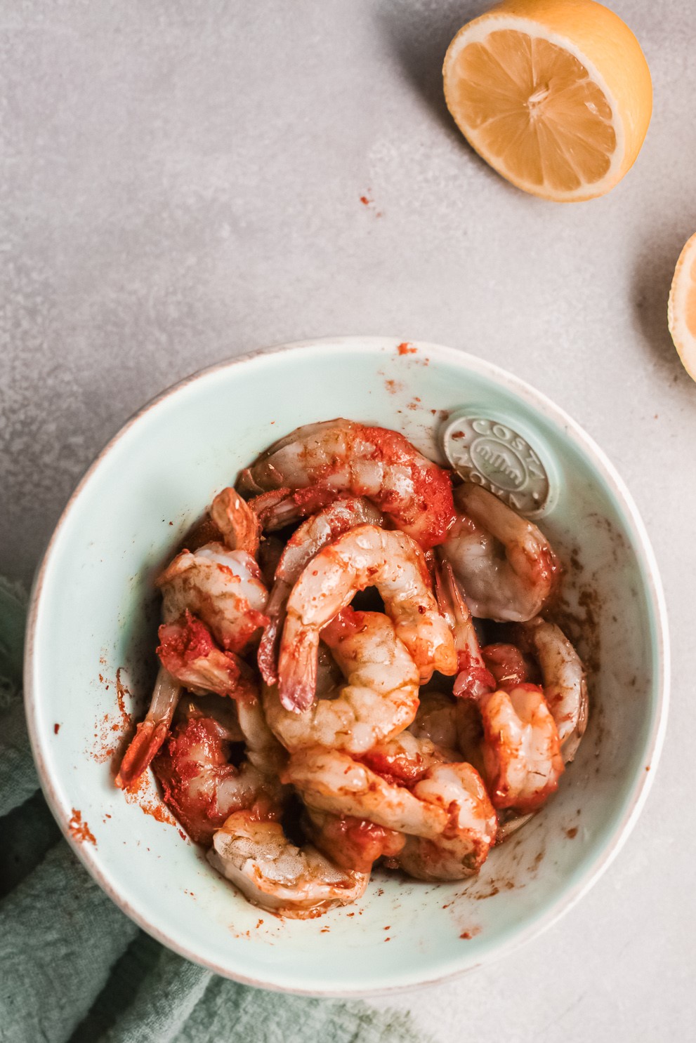Raw shrimp in a bowl covered in cajun seasoning