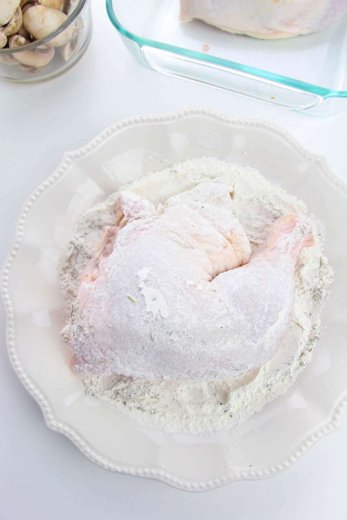 Dredging chicken in flour in a bowl.
