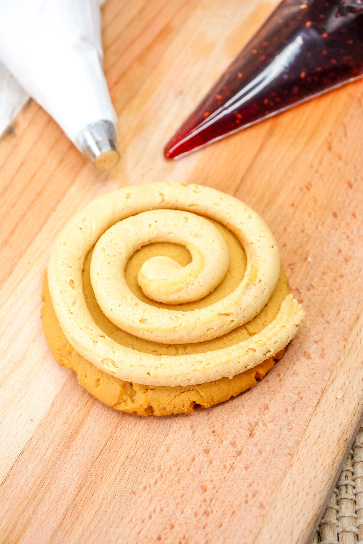 Frosting the peanut butter cookie with a large spiral of peanut butter frosting.