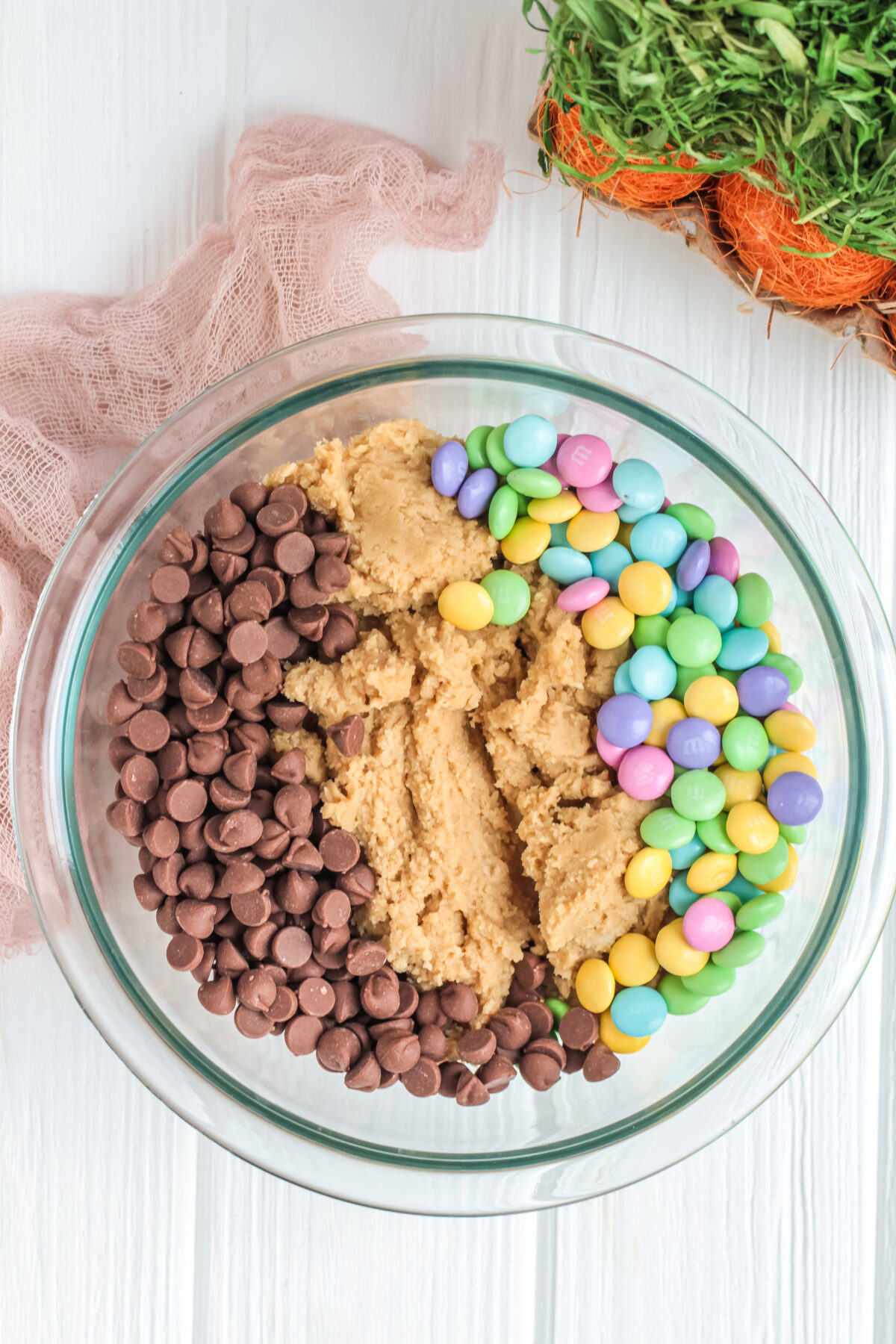 Cookie dough in a bowl with chocolate chips and easter m&ms.
