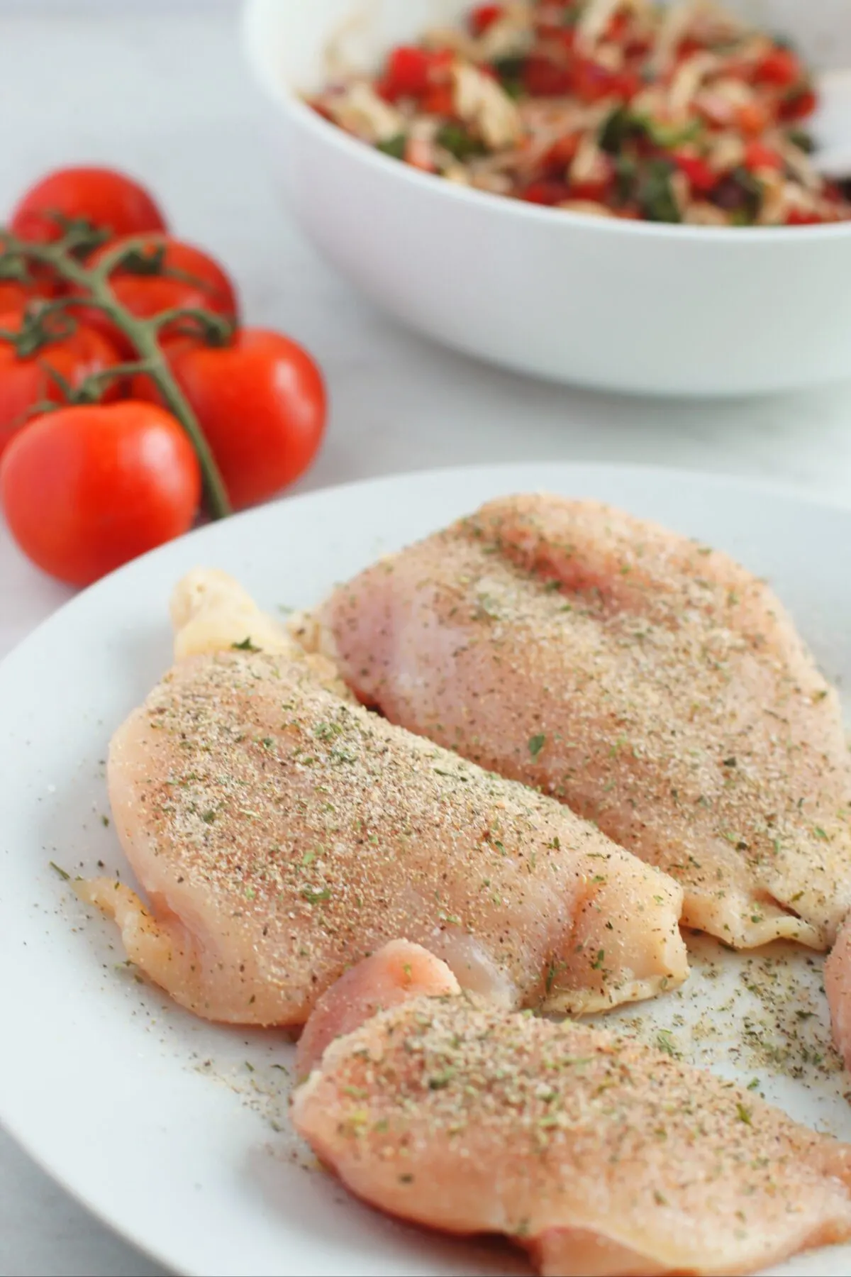 Raw chicken breasts with seasoning.