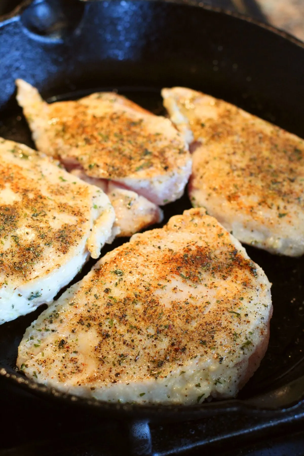 Chicken cooking in a cast iron pan.
