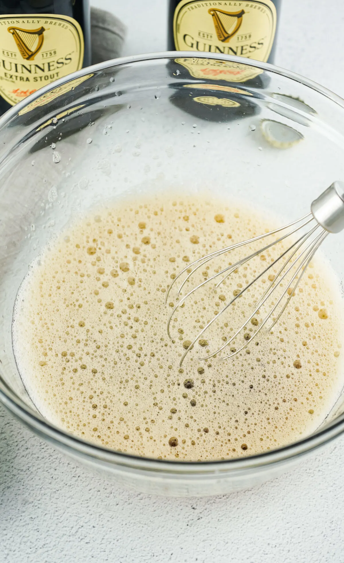 Frothy liquid in a bowl with a whisk.