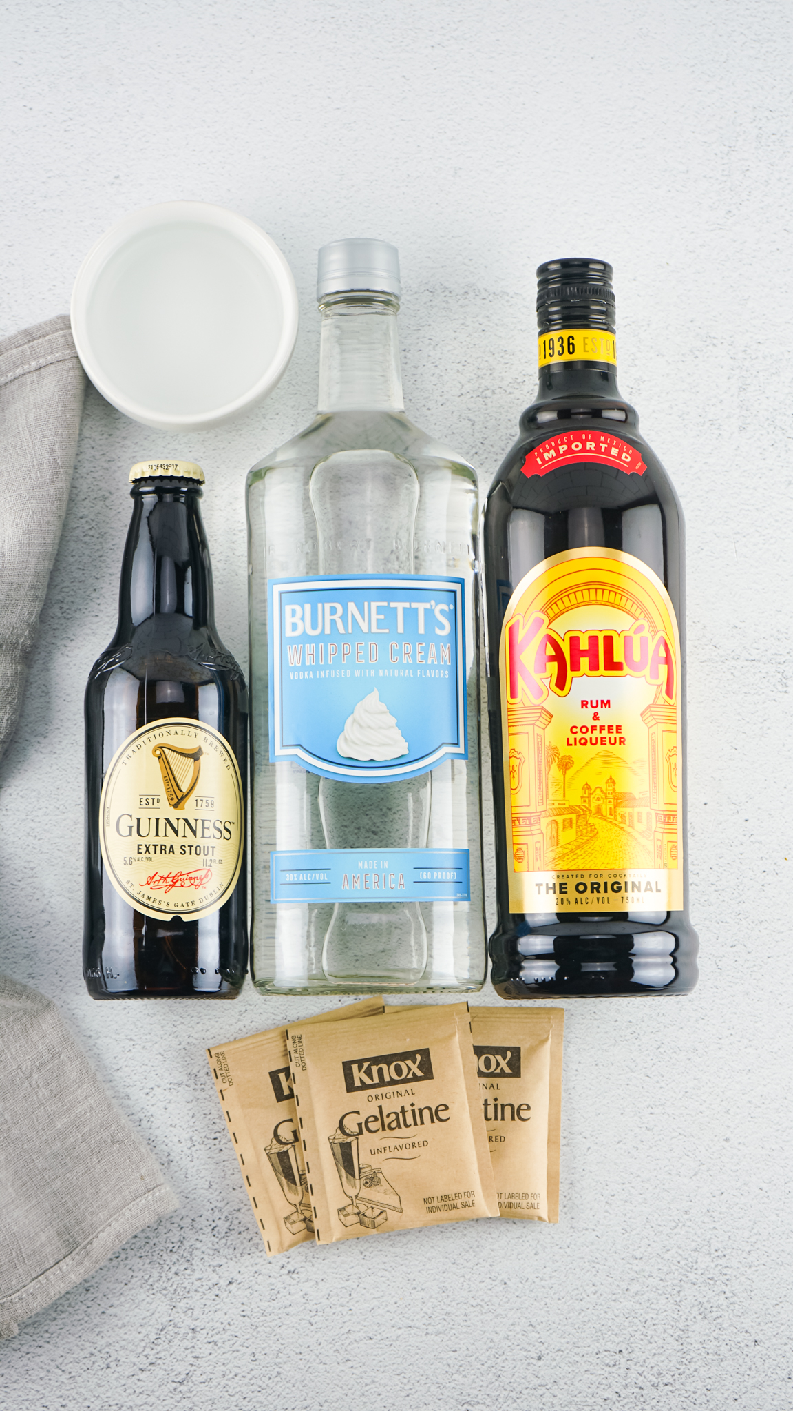 Ingredients for Guinness jello shots - packets of knox gelatin, guinness extra stout bottle, Burnett's whipped cream vodka, and Kahlua.