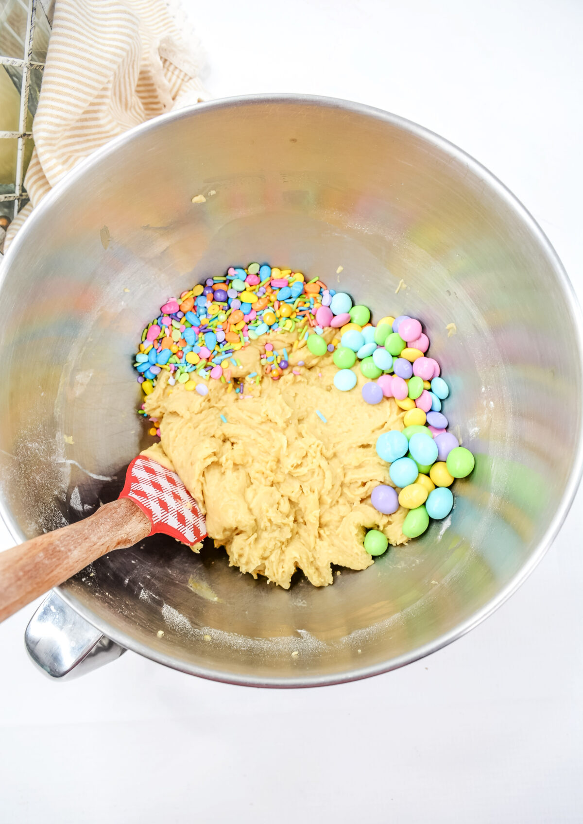 Stirring m&ms into cookie batter in a large mixing bowl.