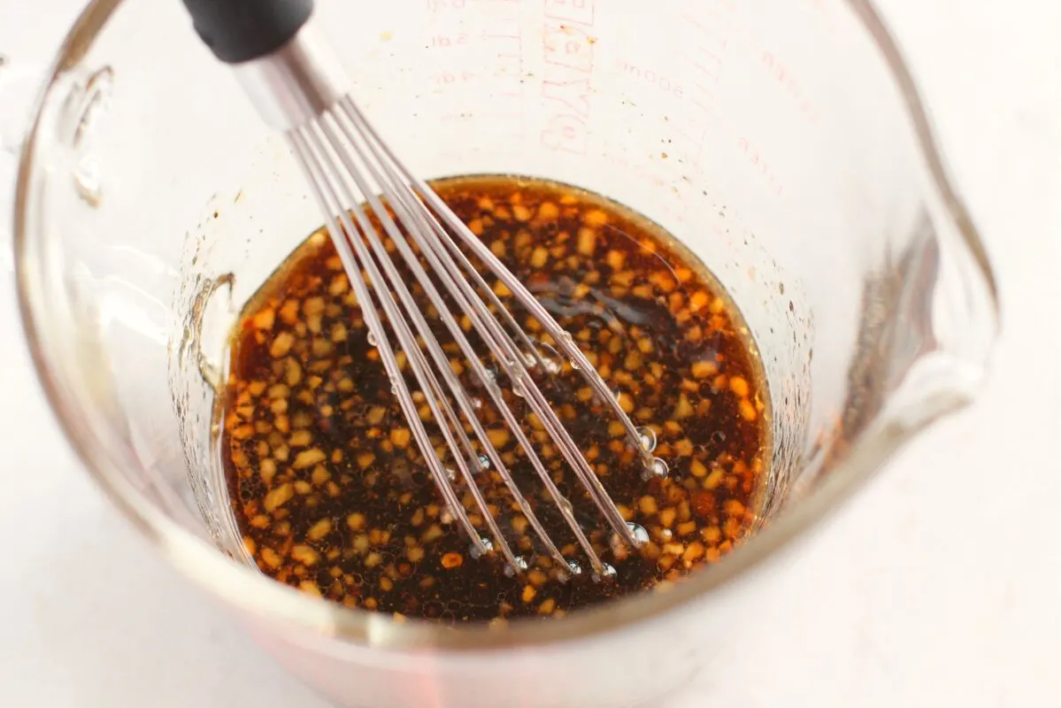 Teriyaki sauce being prepared in a bowl with a whisk.