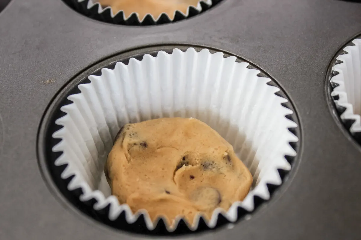 Raw cookie dough in the bottom of a cupcake liner.