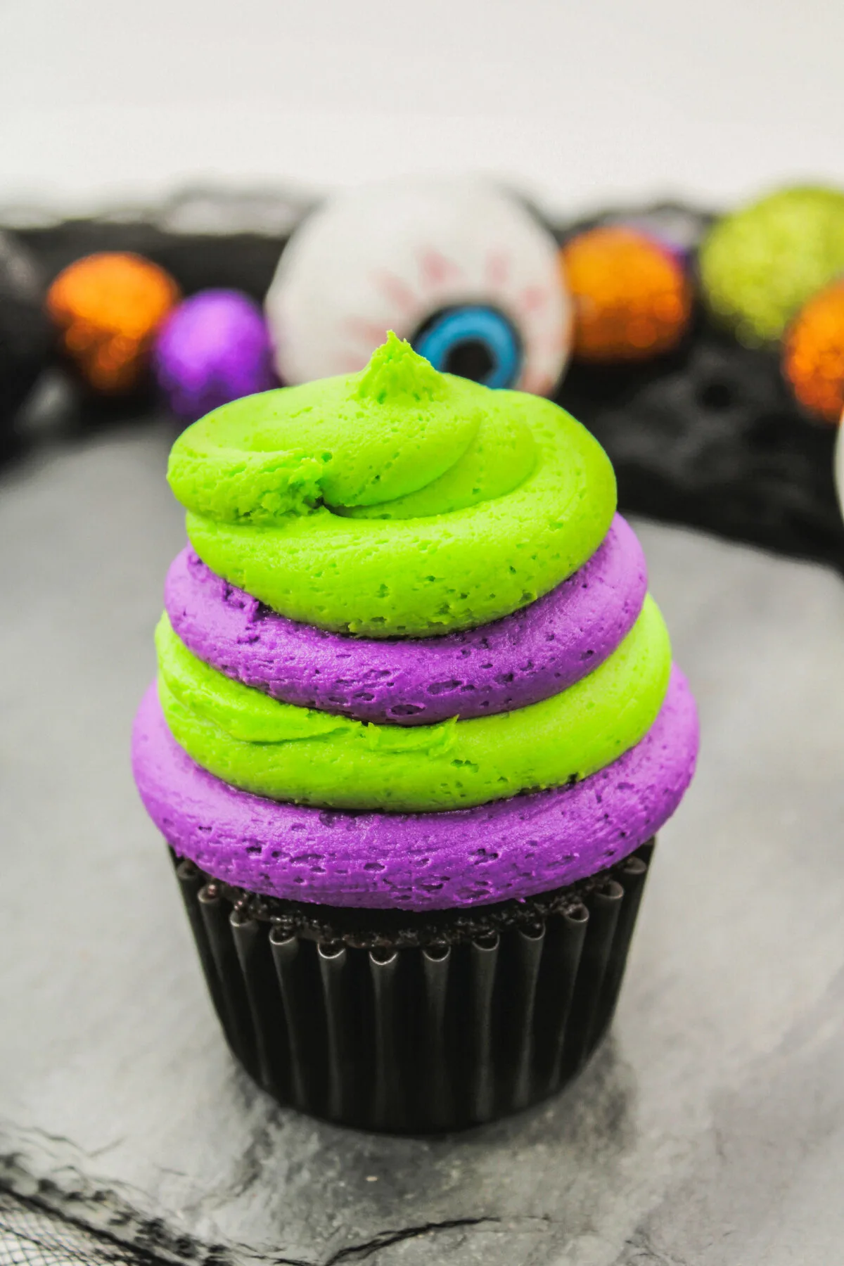Cupcake with layers of purple and green frosting,
