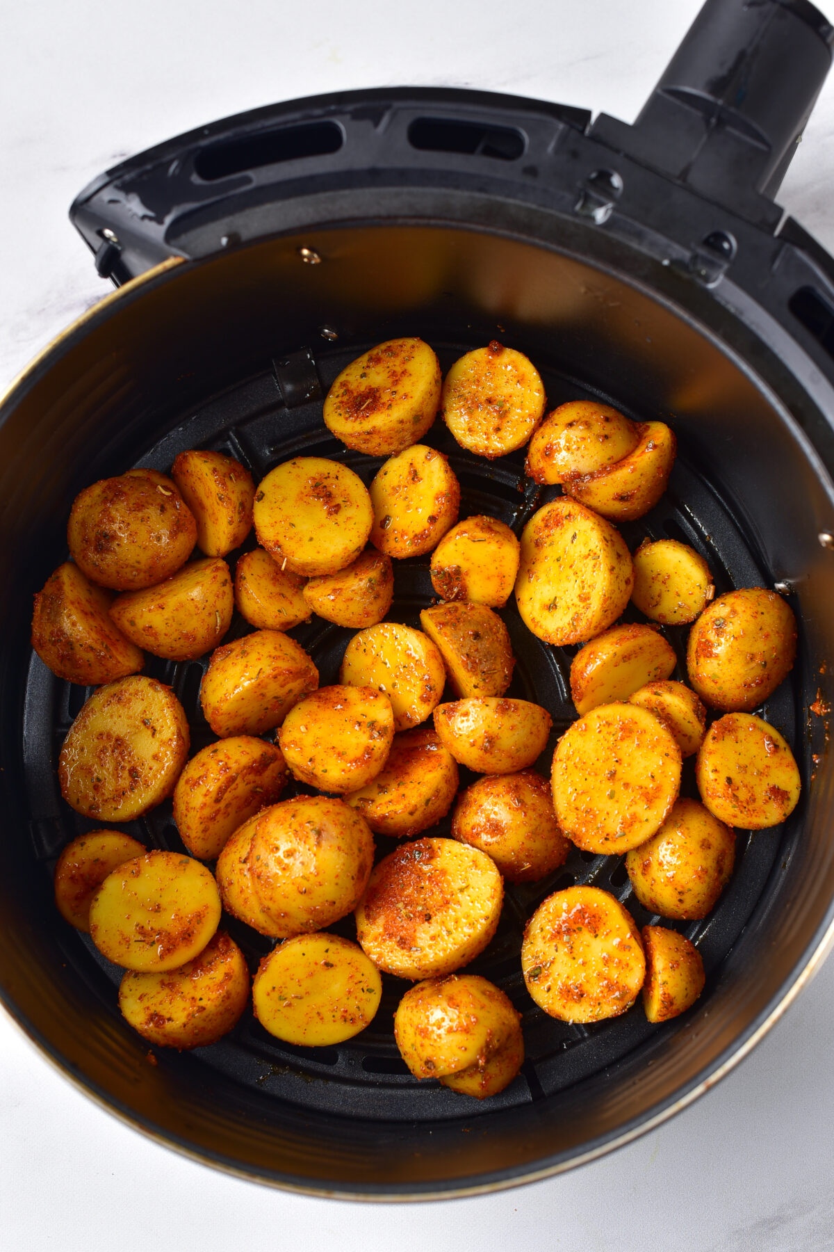 Seasoned baby potatoes in the air fryer basket.