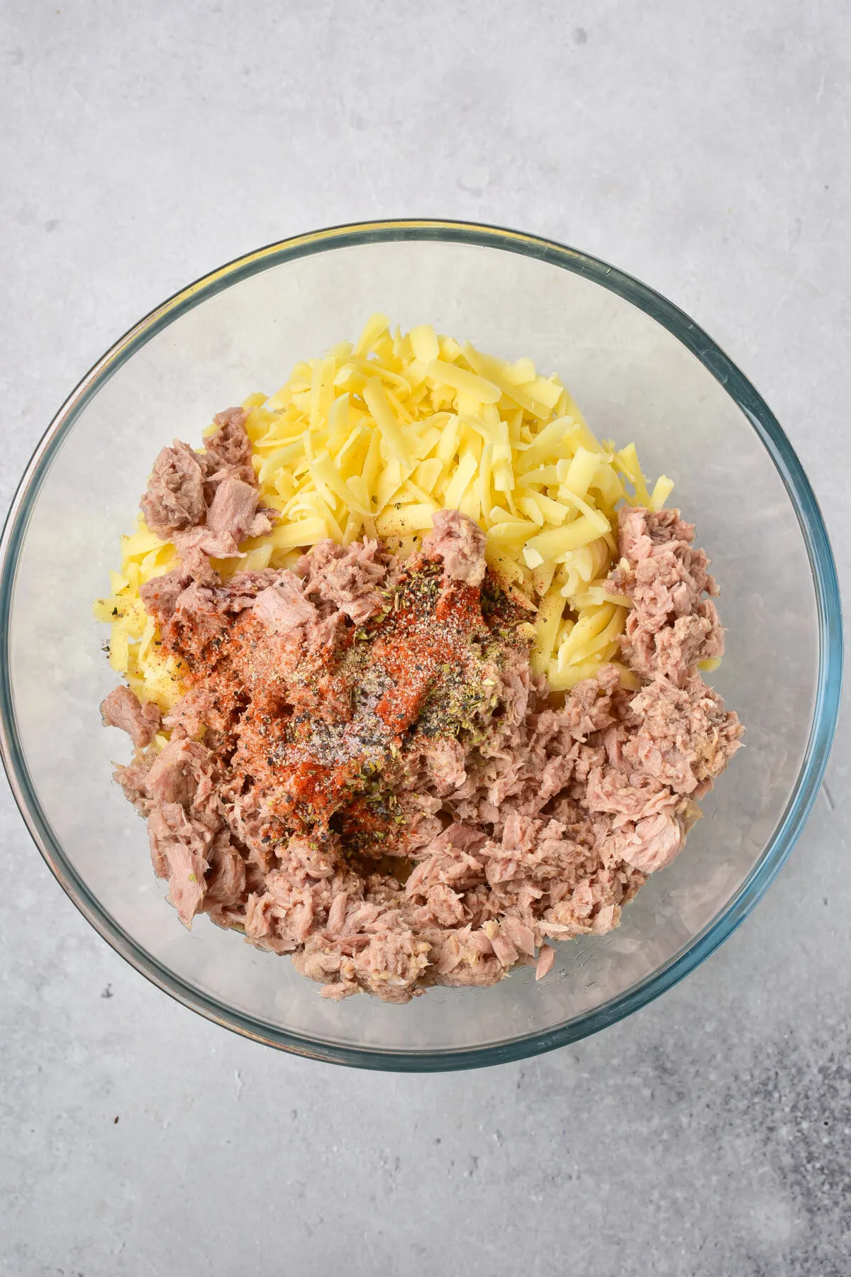 Tuna, pasta, cheddar, salt and seasonings in a large glass bowl.
