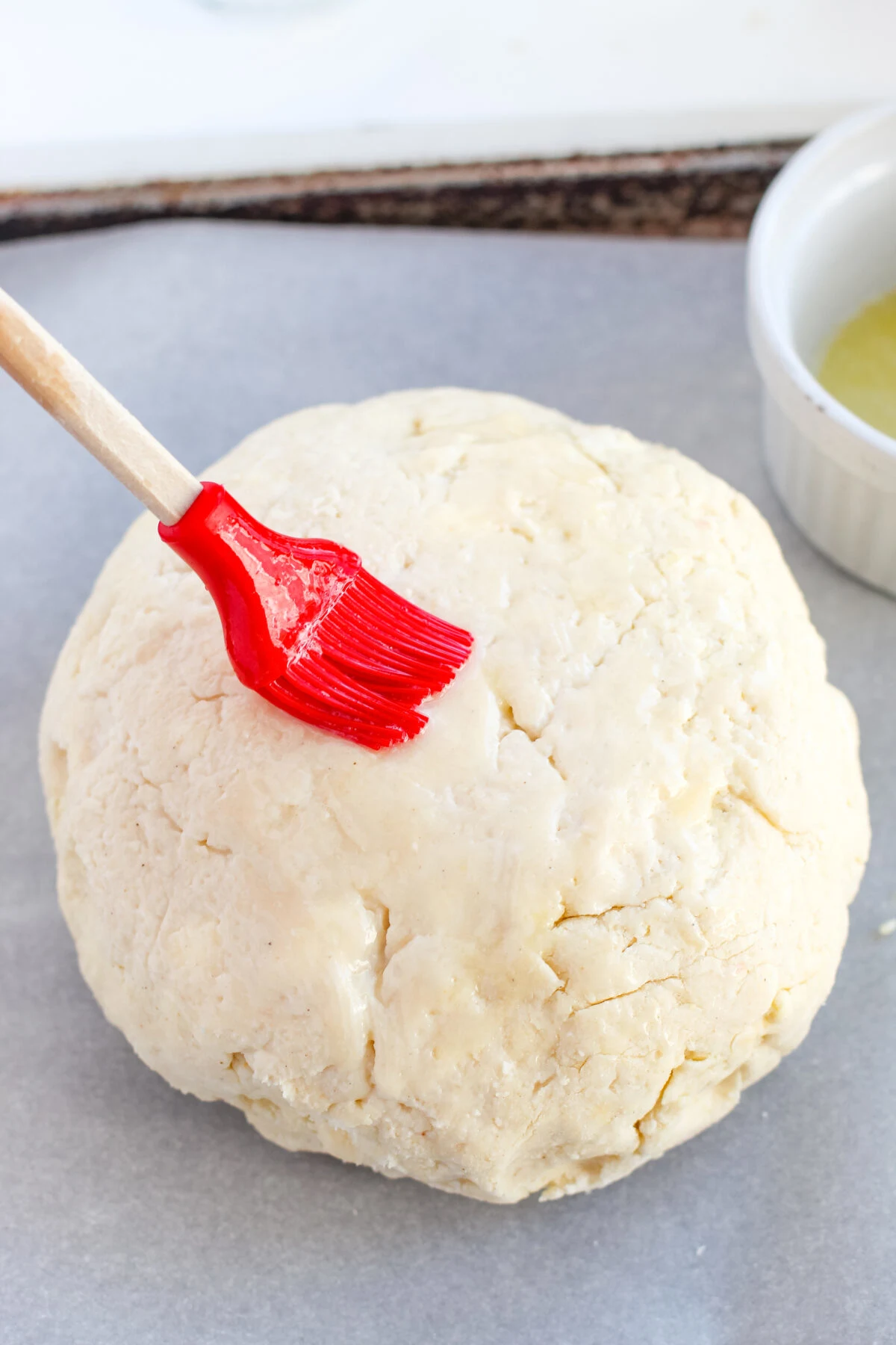 Dough ball being brushed over with melted butter.