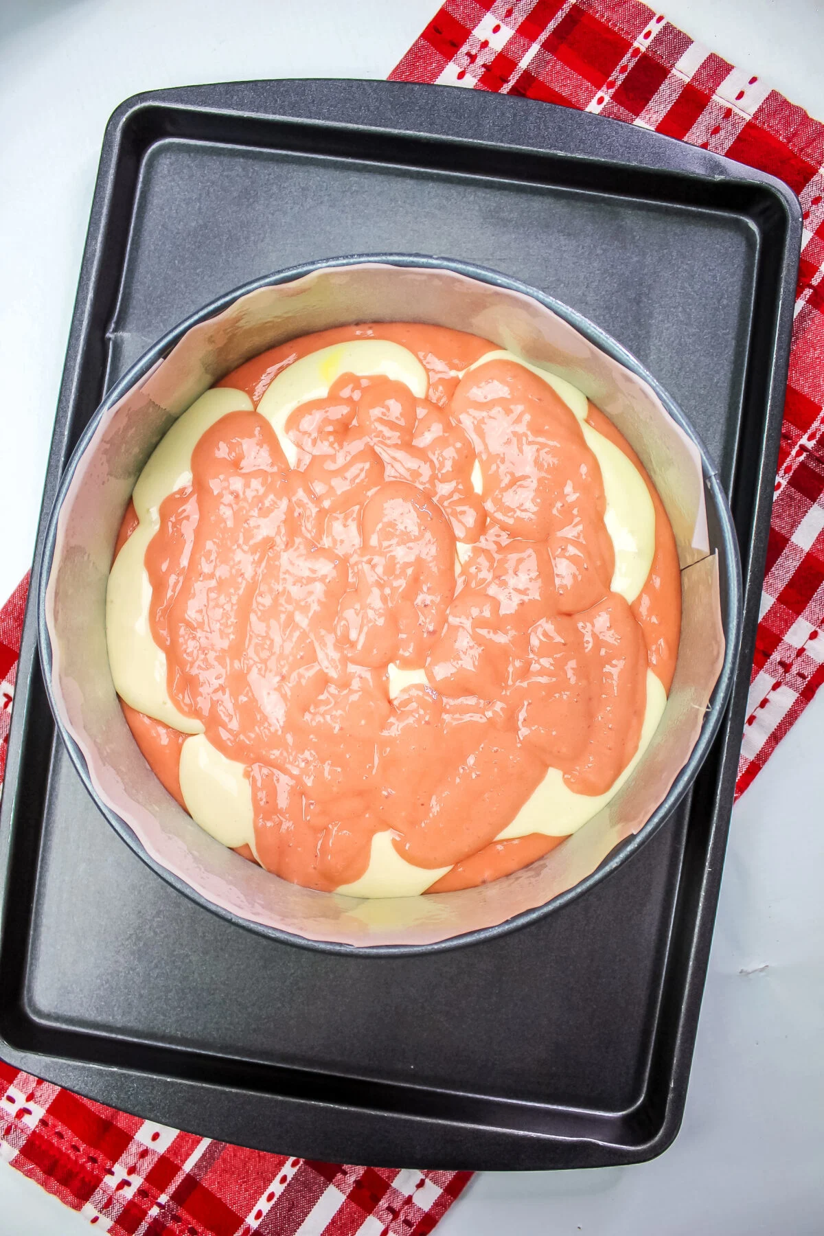 Strawberry cake batter poured over the cheesecake filling.