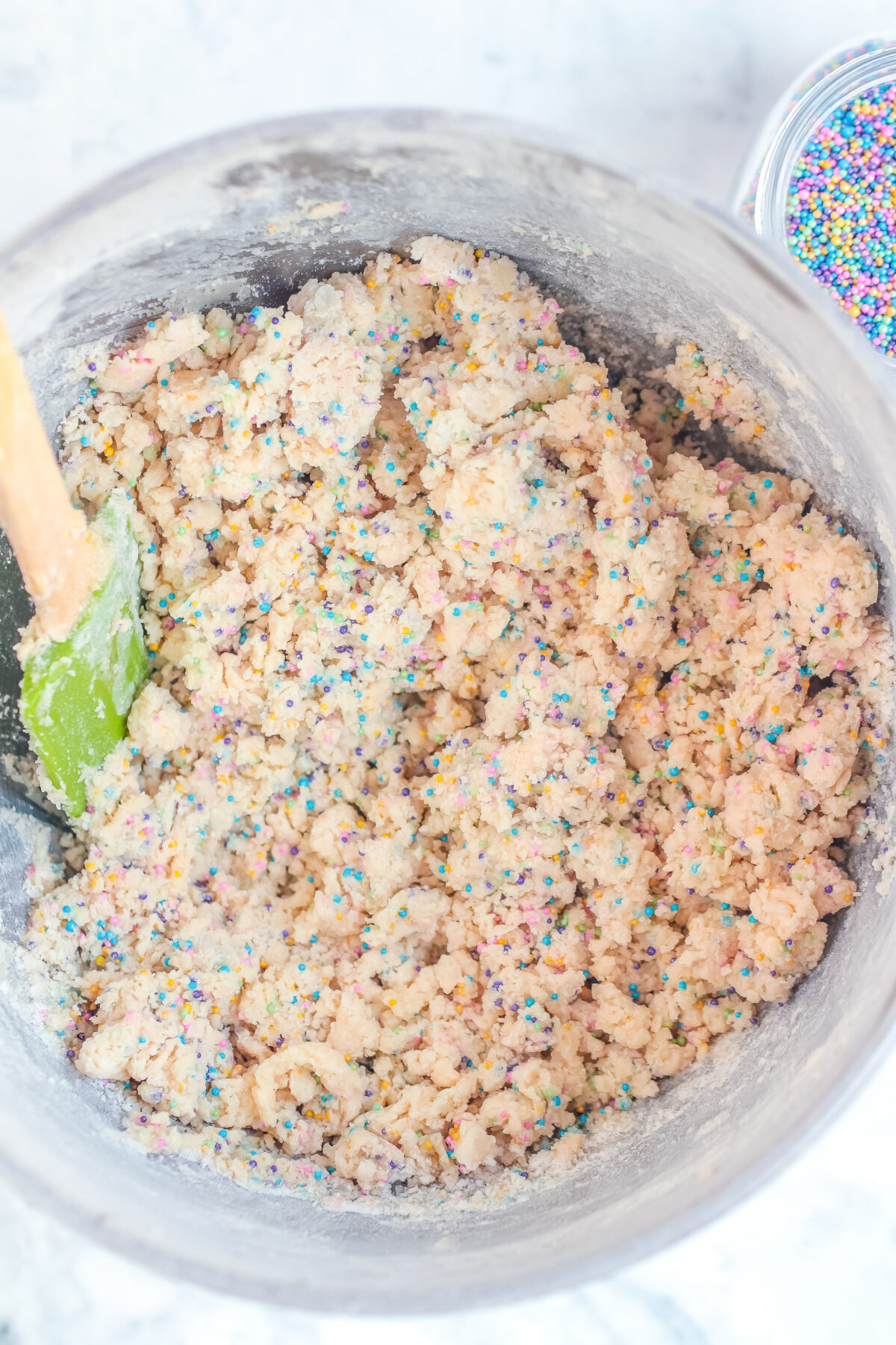 Cookie dough in a bowl with sprinkles being mixed in.